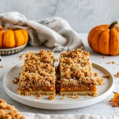 two pieces of pie on a plate with pumpkins in the background