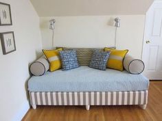 a couch sitting in the middle of a living room with pillows on it's back