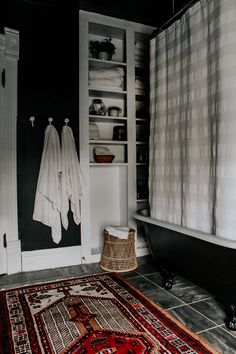 a bathroom with a rug, bathtub and towel rack in black and white colors