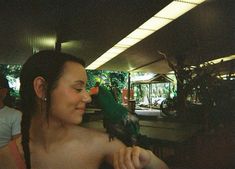 a woman holding a green bird on her arm