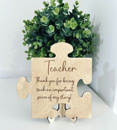 a wooden puzzle with the words teacher on it and a potted plant in the background