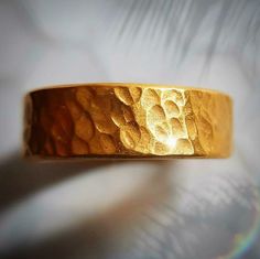 This is a thick and hefty solid 24k gold band with a hammered finish. The ring is approximately 6 MM wide. 24k gold is relatively soft, but the thickness and irregular handmade finish makes this ring wearable. This is a serious chunk of gold, and the color of real 24k gold really has no match, it is absolutely beautiful. Even if you look for one, there are not many rings available like this. The size is an 9, but I can make it any size. Also, I can make this in 22k gold, which is slightly more d Handmade Gold Rings With Thick Band, Gold Thick Band With Adjustable Fit, Gold Adjustable Thick Band, Adjustable Thick Gold Band, Gold Hammered Wide Band Ring For Anniversary, Gold Hammered Wedding Bands, Adjustable Gold Wide Band Wedding Ring, Adjustable Gold Wide Band Ring For Wedding, Hammered Gold Band For Anniversary