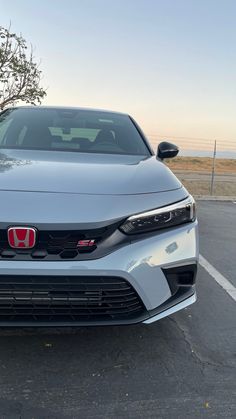 the front end of a silver car parked in a parking lot