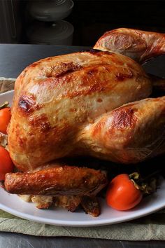 a roasted turkey on a white plate with tomatoes and carrots, ready to be eaten