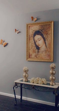 a painting hangs on the wall next to a table with vases and other decorations