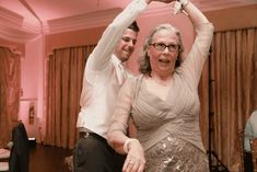 a man and woman are dancing together in a room with pink lighting on the walls