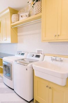 a washer and dryer sitting in a kitchen next to each other with yellow cabinets