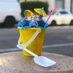 a yellow cup filled with ice cream and sprinkles next to a white plastic spoon