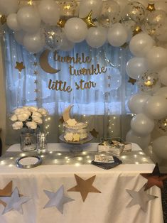 a table topped with balloons and stars next to a window filled with white flowers in vases