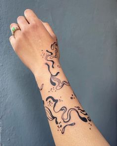 a woman's arm with a black and white tattoo design on the left wrist