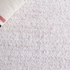 a close up view of the corner of a white rug with a black and red stripe on it