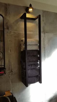 towels are stacked up in the corner of a bathroom with a light on above it