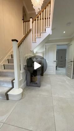 an empty house with stairs and a chandelier in the hallway, next to a white staircase