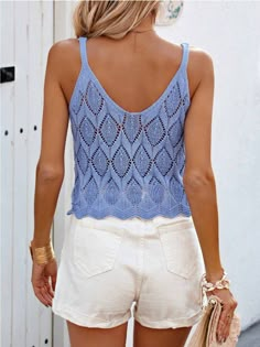 a woman wearing white shorts and a blue tank top is holding a handbag in her left hand