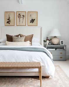 a white bed sitting in a bedroom next to two framed pictures