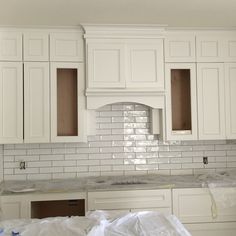 a kitchen with white cabinets and tile backsplashes in the process of remodeling