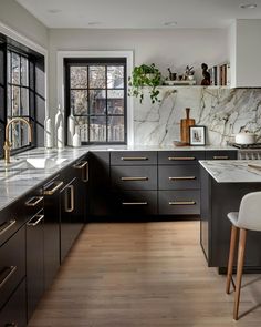 a kitchen with marble counter tops and black cabinets, along with white chairs in front of the window