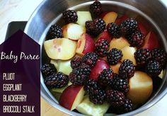 a metal bowl filled with fruit on top of a wooden table