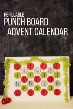 a calendar made out of paper with red and green circles on it, sitting next to a chalkboard