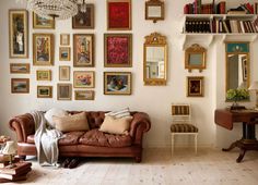 a living room filled with furniture and lots of framed pictures on the wall above it