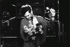 black and white photograph of a man holding flowers in his hand while standing on stage