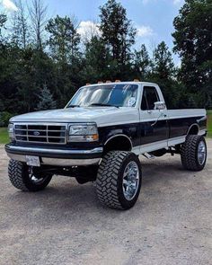 a large truck parked on top of a parking lot next to some grass and trees