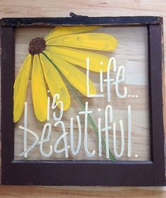 a wooden sign that says life is beautiful with a yellow flower in the center and words below it