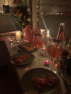 two plates with food and wine on a table in front of candles, flowers and other items