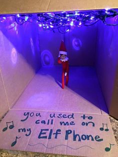 an elf in a box with music notes on the floor and lights strung from the ceiling