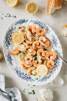 a plate with shrimp and lemons on it next to bread, garlic and parsley