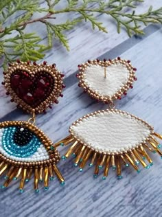 three pairs of beaded earrings on top of a wooden table next to a plant