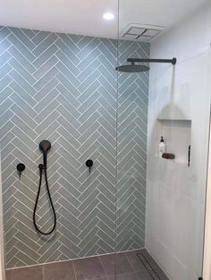 a walk in shower sitting next to a glass door and tiled wall with black fixtures