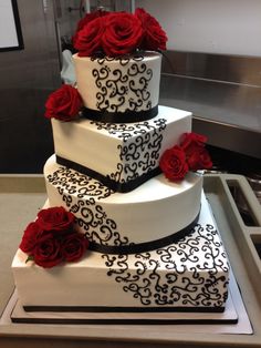 a three tiered cake with red roses on the bottom and black trimmings