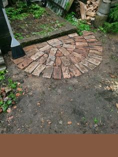 a brick patio with a broom laying on it's side in the middle of an overgrown yard