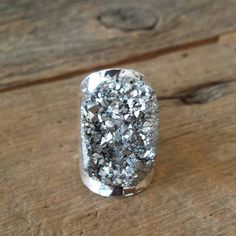 a close up of a silver ring on a wooden table with wood planks in the background