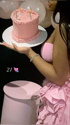 a woman in a pink dress holding a birthday cake