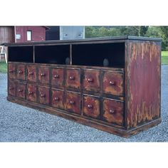 an old dresser with many drawers and knobs on the doors is sitting in gravel