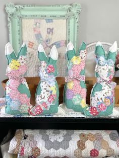 three small stuffed animals sitting on top of a table next to a pillow and quilt