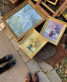 there are many framed pictures on the ground next to each other and one person's shoes