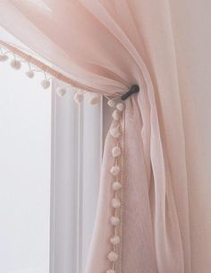 a pink curtain with pom poms hanging from it