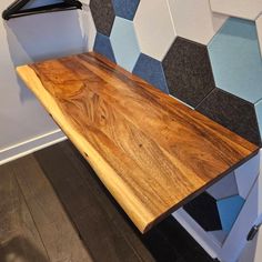 a wooden table sitting in front of a wall with hexagonal tiles on it