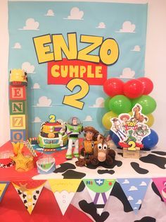 a table topped with toys and balloons next to a sign that says enzo cumple