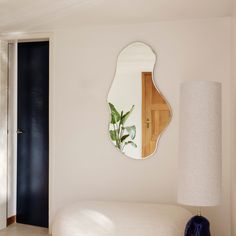 a mirror on the wall above a bed in a room with white walls and flooring