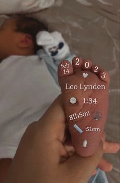 a baby's hand holding up a birth stone with numbers and symbols on it