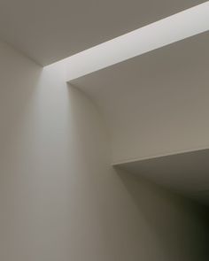 an empty room with white walls and light coming from the ceiling