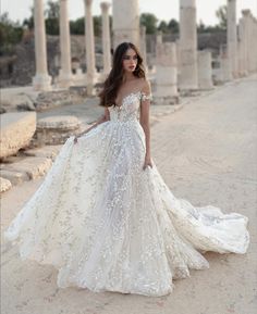 a woman in a wedding dress standing on the side of an old building with columns