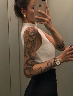 a woman taking a selfie in the mirror with her cell phone and tattoos on her arm