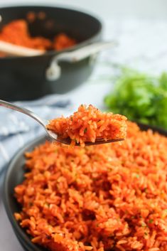 a spoon full of carrot rice on top of a bowl