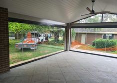 an empty room with large windows and a truck parked in the back yard behind it