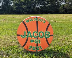 an orange and white sign with the words wildcats jacob on it in grass